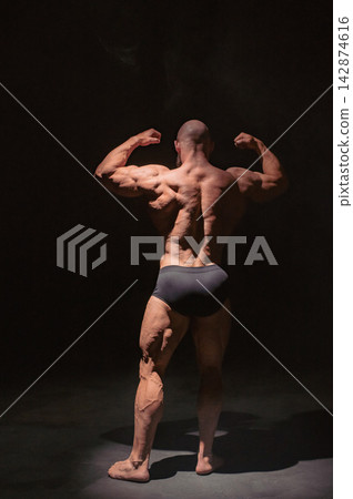 A male bodybuilder poses in shorts, showing off his muscles. A male bodybuilder poses in shorts, showing off his muscles. 142874616
