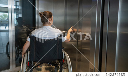 A Caucasian woman in a wheelchair uses an elevator. A Caucasian woman in a wheelchair uses an elevator. 142874685