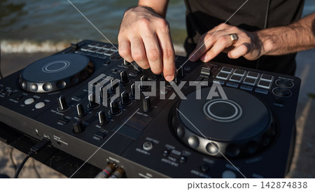 Close up of DJ's hands while working outdoors. Close up of DJ's hands while working outdoors. 142874838