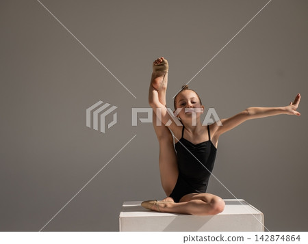 Little gymnast posing on a white cube on a white background. Little gymnast posing on a white cube on a white background. 142874864