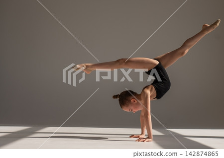 A little girl gymnast does a handstand. Copy space.  142874865