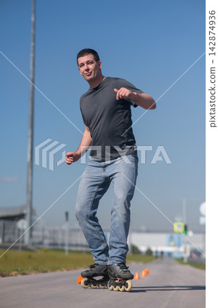 A Caucasian man rollerblades around the slalom course. A Caucasian man rollerblades around the slalom course. 142874936