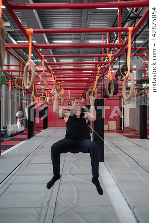 An athletic man practices at a ninja club's indoor obstacle course. An athletic man practices at a ninja club's indoor obstacle course. 142875054