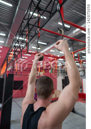 An athletic man practices at a ninja club's indoor obstacle course. 142875056