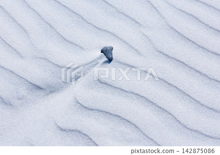 Close-up abstract of perfect wind ripple patterns in white sand dunes forming gentle waves Close-up abstract of perfect wind ripple patterns in white sand dunes forming gentle waves 142875086
