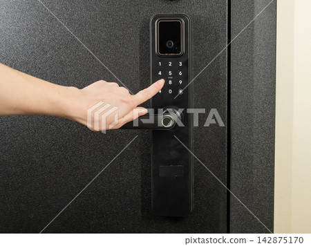 A woman opens a modern smart door lock with a digital keypad using a code. A woman opens a modern smart door lock with a digital keypad using a code. 142875170