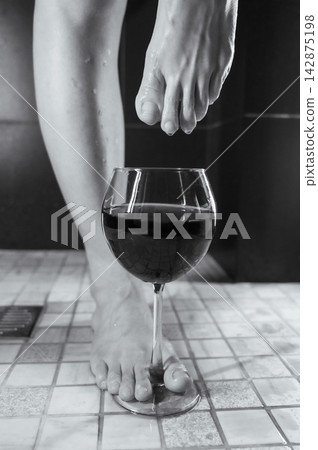Foot fetish. A woman dips her toes in a glass of red wine. Foot fetish. A woman dips her toes in a glass of red wine. 142875198