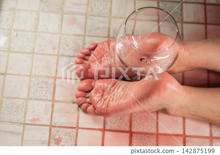 Foot fetish. A woman holds a wine glass in the shower. Foot fetish. A woman holds a wine glass in the shower. 142875199