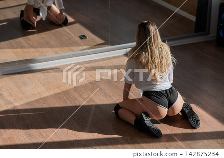 A young woman dances twerk in short shorts in front of a mirror. 142875234