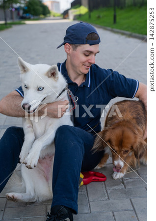 A man hugs his two dogs while on a walk. A man hugs his two dogs while on a walk. 142875253