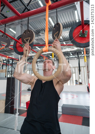 An athletic man practices at a ninja club's indoor obstacle course. 142875313