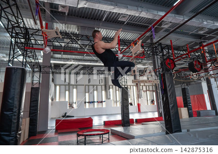 An athletic man practices at a ninja club's indoor obstacle course. An athletic man practices at a ninja club's indoor obstacle course. 142875316