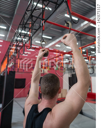 An athletic man practices at a ninja club's indoor obstacle course. An athletic man practices at a ninja club's indoor obstacle course. 142875317