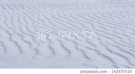 Close-up abstract of perfect wind ripple patterns in white sand dunes forming gentle waves Close-up abstract of perfect wind ripple patterns in white sand dunes forming gentle waves 142875510