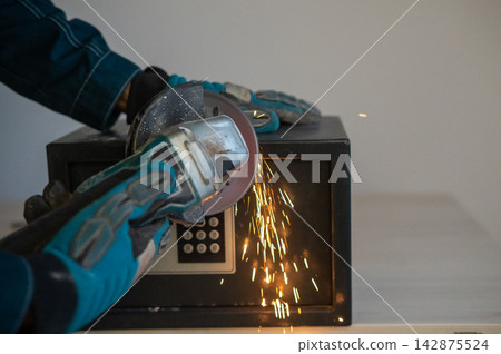 A man breaks into a safe with a grinder. A man breaks into a safe with a grinder. 142875524