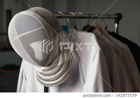 Fencing uniforms and masks hang on hangers. No people.  142875579