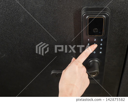 A woman opens a modern smart door lock with a digital keypad using a code. 142875582