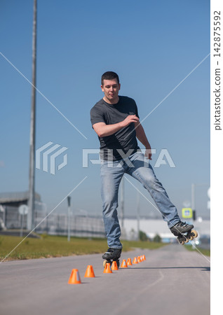 A Caucasian man rollerblades around the slalom course. A Caucasian man rollerblades around the slalom course. 142875592