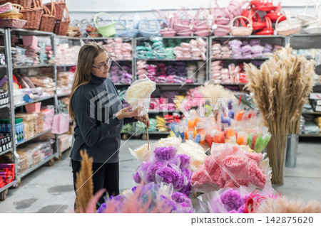 A Caucasian woman buys dried flowers at a home decor store. 142875620