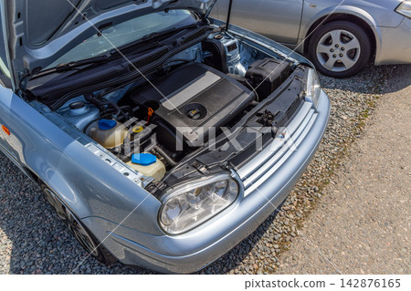 Close-up view of silver used German car engine compartment under sunlight Close-up view of silver used German car engine compartment under sunlight 142876165