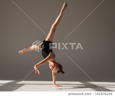 A little girl gymnast does a handstand. Copy space. A little girl gymnast does a handstand. Copy space. 142876209
