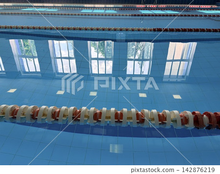 An empty swimming pool with red and white buoys. Concept of sports competitions and active lifestyle. An empty swimming pool with red and white buoys. Concept of sports competitions and active lifestyle. 142876219