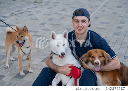 A man hugs his two dogs while on a walk. A man hugs his two dogs while on a walk. 142876287