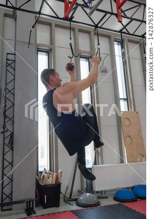 An athletic man practices at a ninja club's indoor obstacle course. An athletic man practices at a ninja club's indoor obstacle course. 142876327