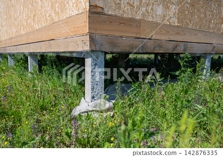 A close-up of concrete piles on a country house under construction. Cottage foundation. A close-up of concrete piles on a country house under construction. Cottage foundation. 142876335