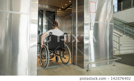 A Caucasian woman in a wheelchair uses an elevator. A Caucasian woman in a wheelchair uses an elevator. 142876402