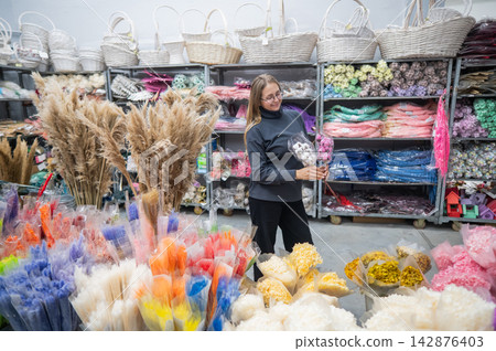 A Caucasian woman buys dried flowers at a home decor store. A Caucasian woman buys dried flowers at a home decor store. 142876403
