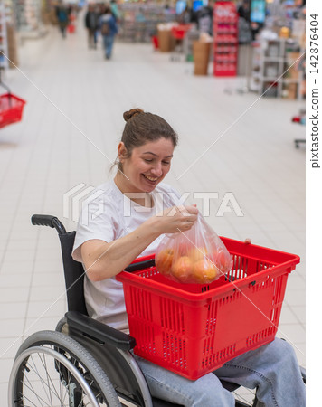 A Caucasian woman in a wheelchair buys fruit at a supermarket. A Caucasian woman in a wheelchair buys fruit at a supermarket. 142876404
