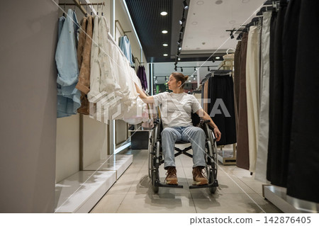 A Caucasian woman in a wheelchair shopping at a mall.  142876405