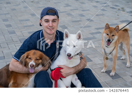A man hugs his two dogs while on a walk. A man hugs his two dogs while on a walk. 142876445