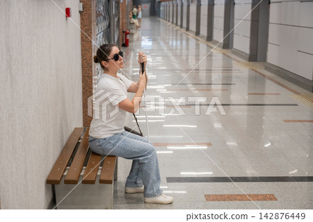 A blind woman waits for a train on the subway. 142876449