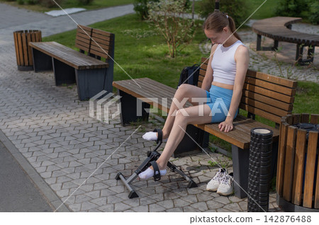 A woman uses Pedal Exercise Machine for self-rehabilitation outdoors. A woman uses Pedal Exercise Machine for self-rehabilitation outdoors. 142876488