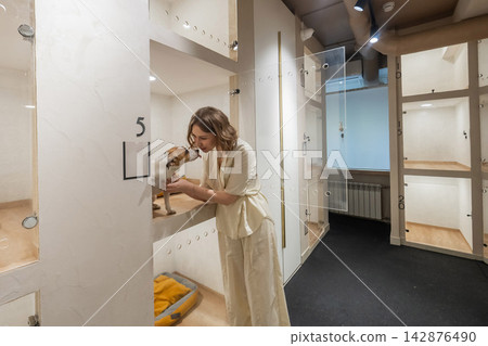 A Jack Russell Terrier at an animal shelter. A dog at an animal shelter in a cage with a glass door. A Jack Russell Terrier at an animal shelter. A dog at an animal shelter in a cage with a glass door. 142876490