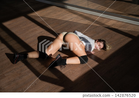 A young woman dances twerk in short shorts on the floor. A young woman dances twerk in short shorts on the floor. 142876520