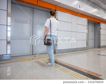 A blind woman waits for a train on the subway. A blind woman waits for a train on the subway. 142876604