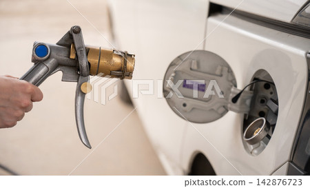 A woman fills a car with gas. Close-up of her hands. A woman fills a car with gas. Close-up of her hands. 142876723
