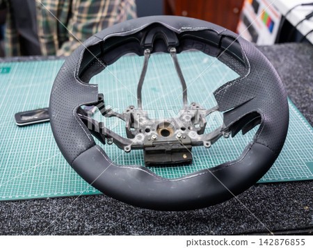 The mechanic changes the cover on the car steering wheel. The mechanic changes the cover on the car steering wheel. 142876855