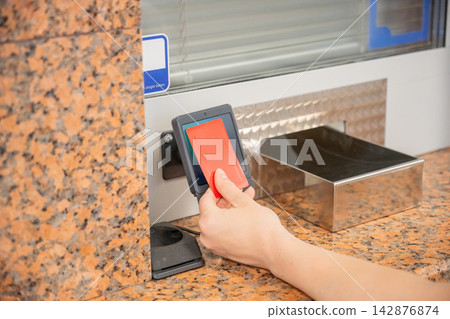 A woman pays for a ride with a bank card at a metro ticket office. A woman pays for a ride with a bank card at a metro ticket office. 142876874