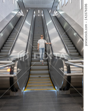A blind woman descends an escalator in the subway. 142876896
