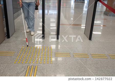 A blind woman walks through a metal detector. A blind woman walks through a metal detector. 142877022