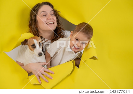 Caucasian little boy, his mother and Jack Russell Terrier dog tearing yellow paper background. Caucasian little boy, his mother and Jack Russell Terrier dog tearing yellow paper background. 142877024