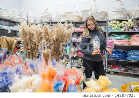 A Caucasian woman buys dried flowers at a home decor store. 142877025