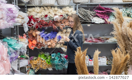 A Caucasian woman buys dried flowers at a home decor store. A Caucasian woman buys dried flowers at a home decor store. 142877027