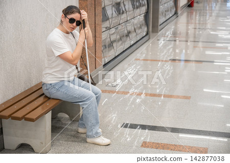 A blind woman waits for a train on the subway. A blind woman waits for a train on the subway. 142877038