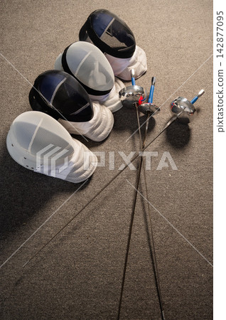 Fencing equipment. Swords and masks on the gray floor. Fencing equipment. Swords and masks on the gray floor. 142877095