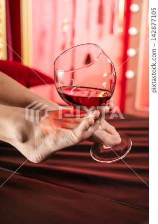 Foot fetish. A woman holds a glass of red wine with her feet. Foot fetish. A woman holds a glass of red wine with her feet. 142877105